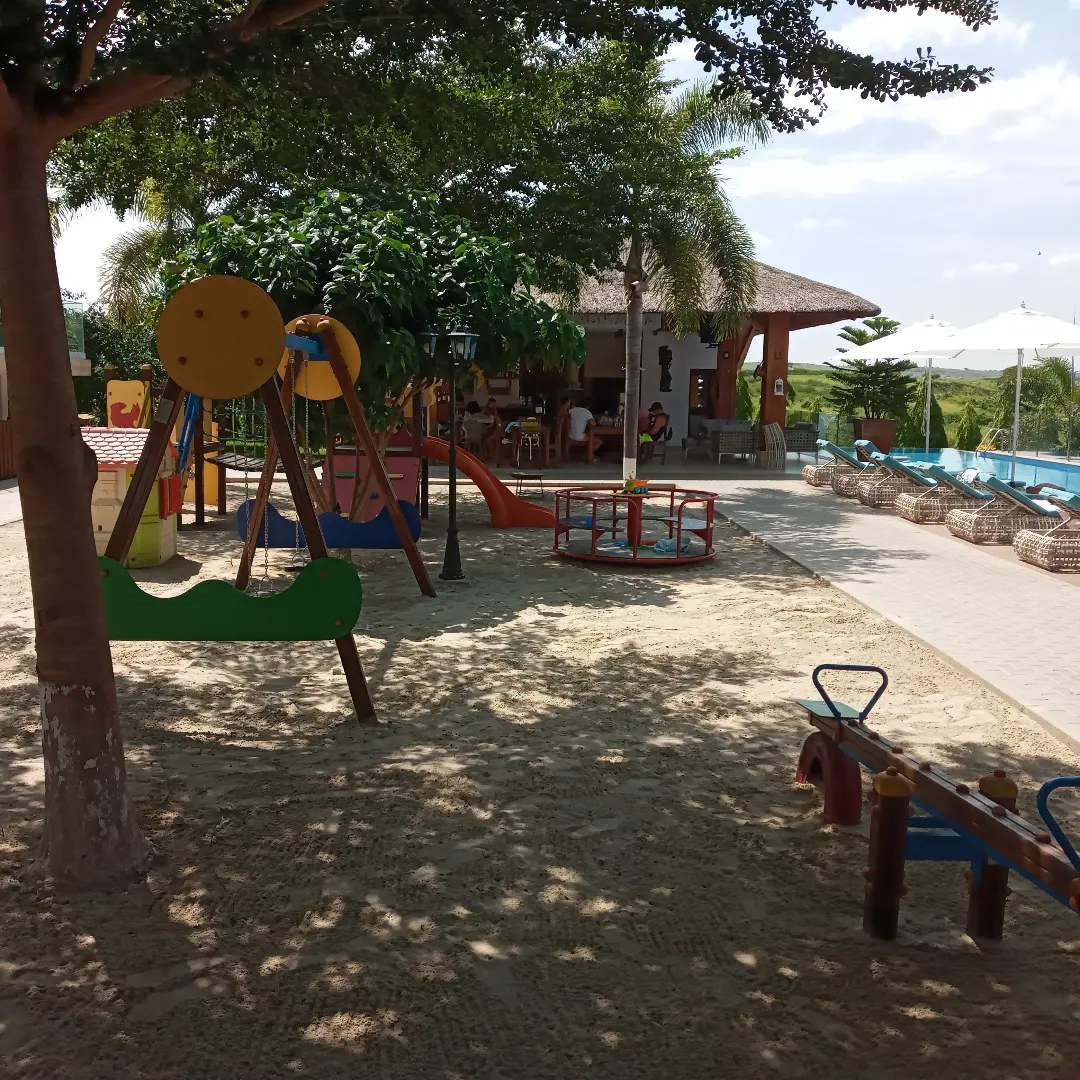 Parque infantil com baloiços e escorrega junto à piscina